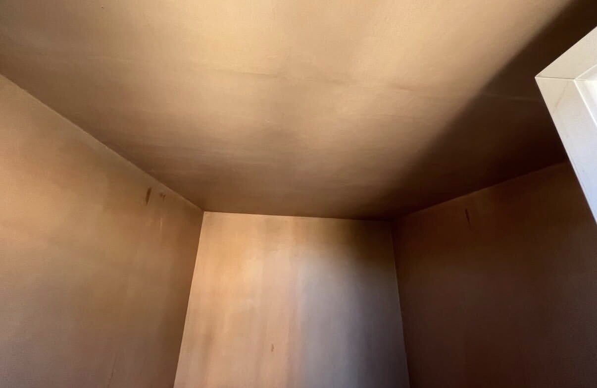 Smooth fresh plaster across the walls and ceiling of a small room